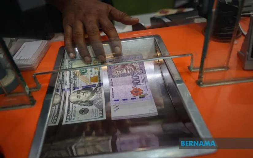 Malaysian ringgit banknotes beside US dollar banknotes